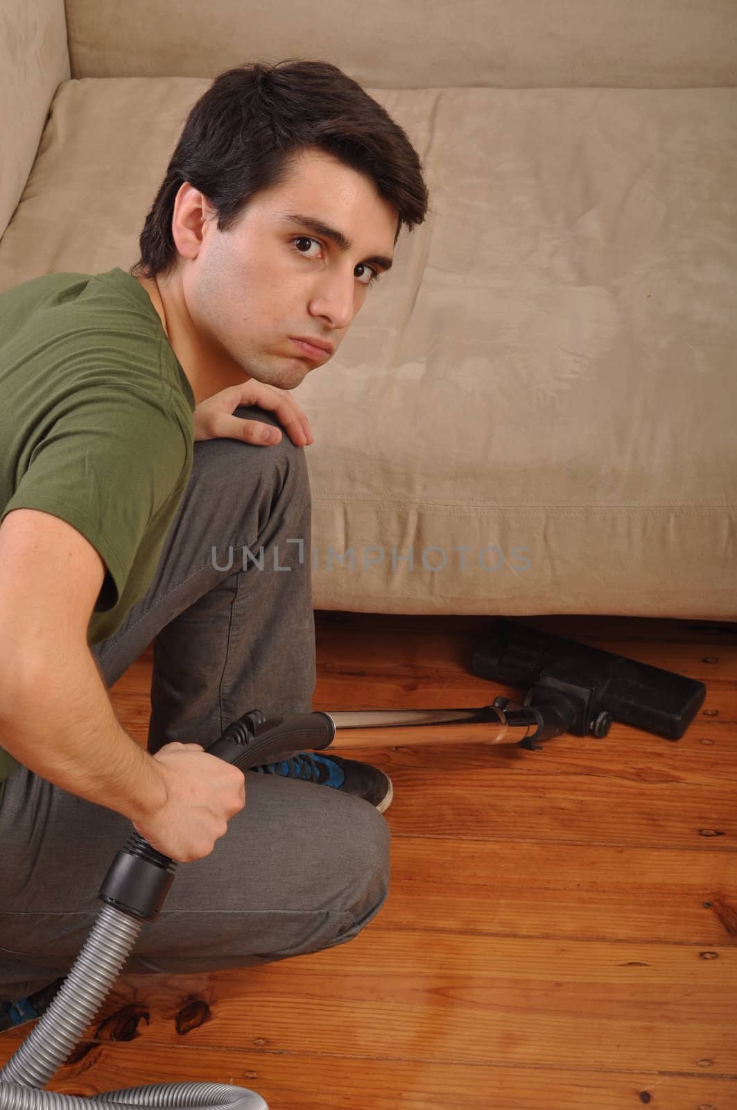 exhausted young man with vacuum cleaner doing the housework