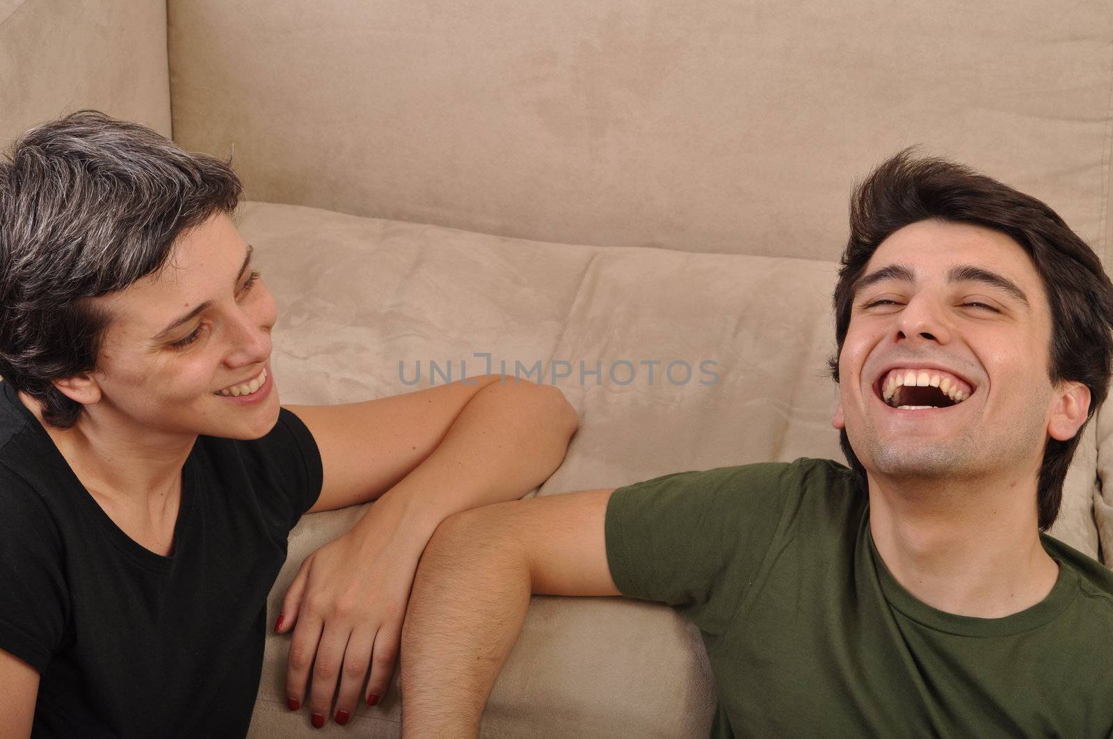 friendship between sister and brother lying and laughing on the floor next to couch
