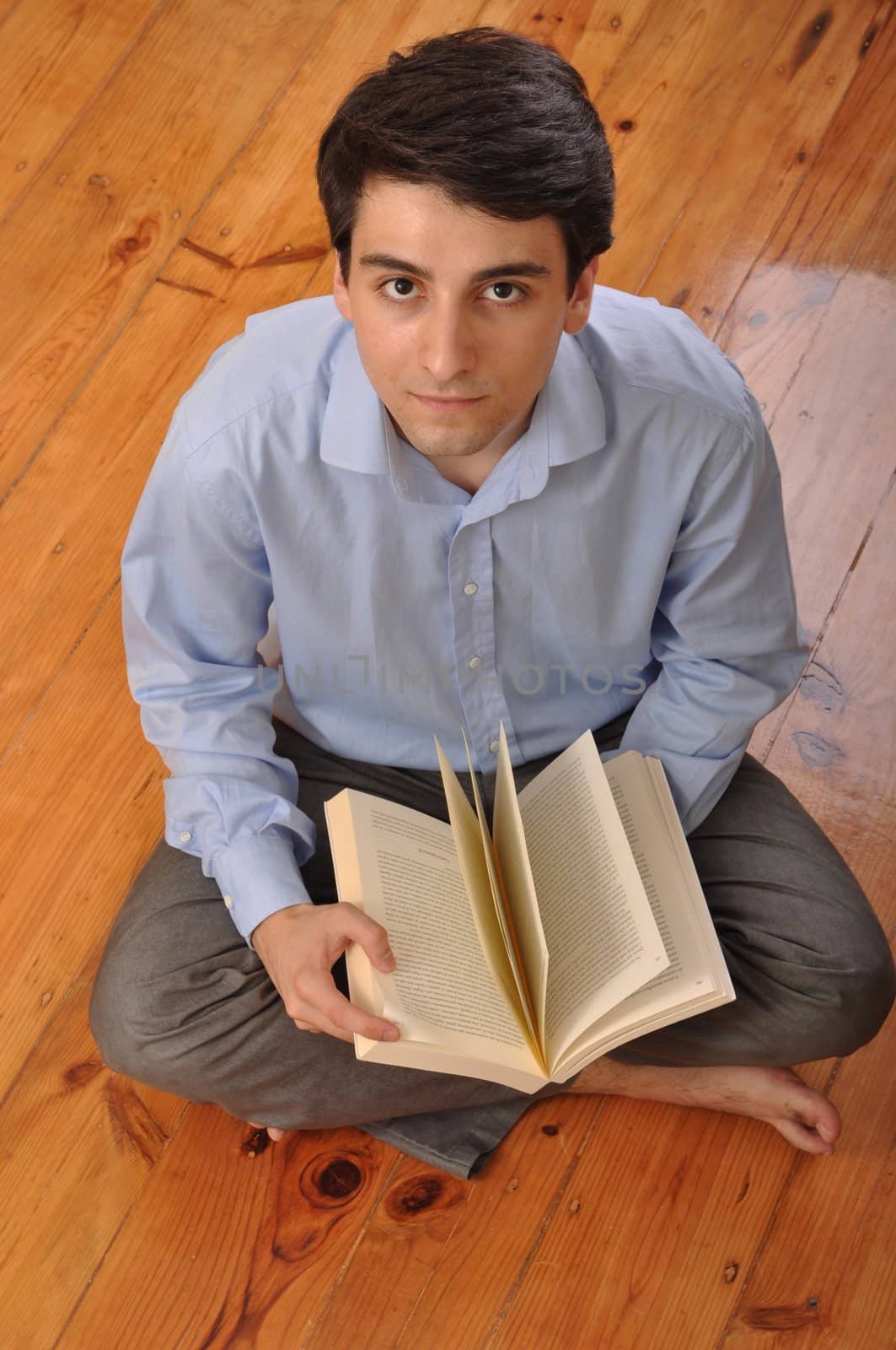 attractive young man reading a business book while sitting on the floor at home