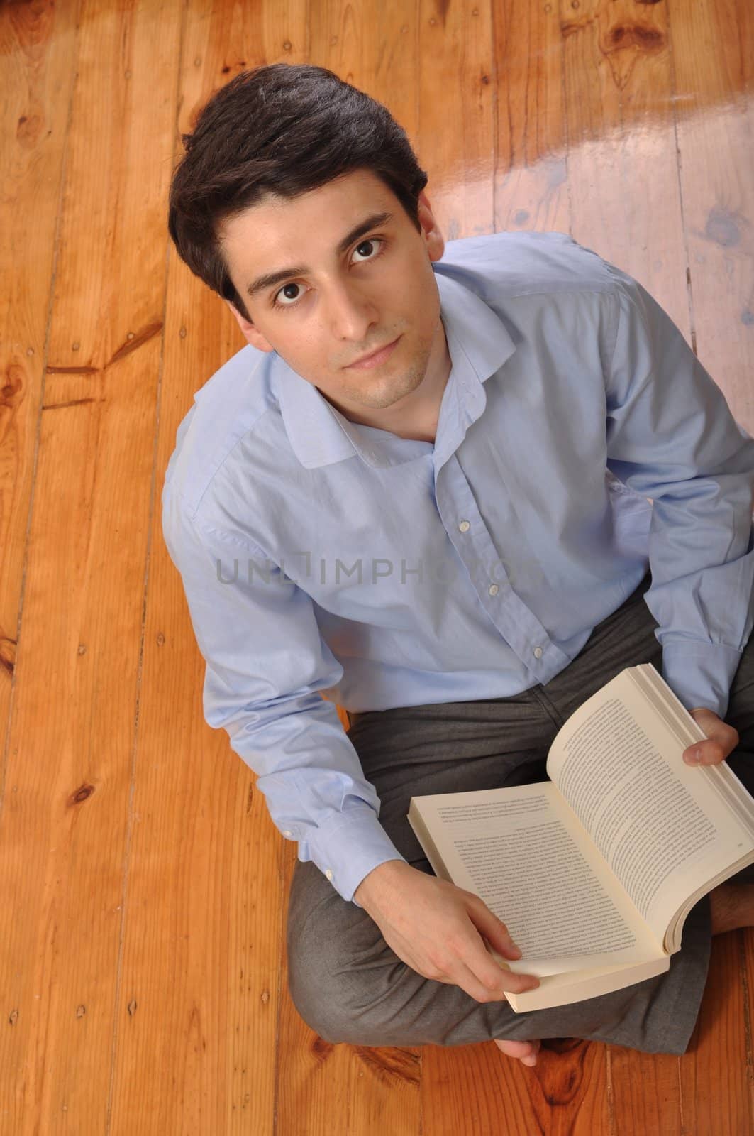 attractive young man reading a business book while sitting on the floor at home