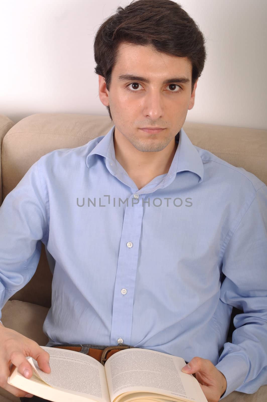 attractive young man reading a business book on the couch