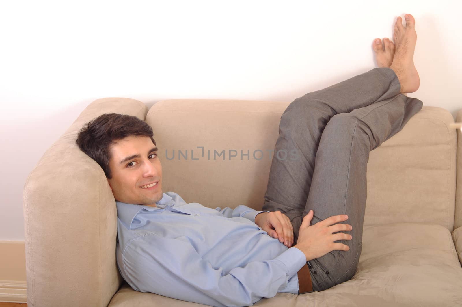 attractive young man lying and relaxing on the couch (isolated on white background)