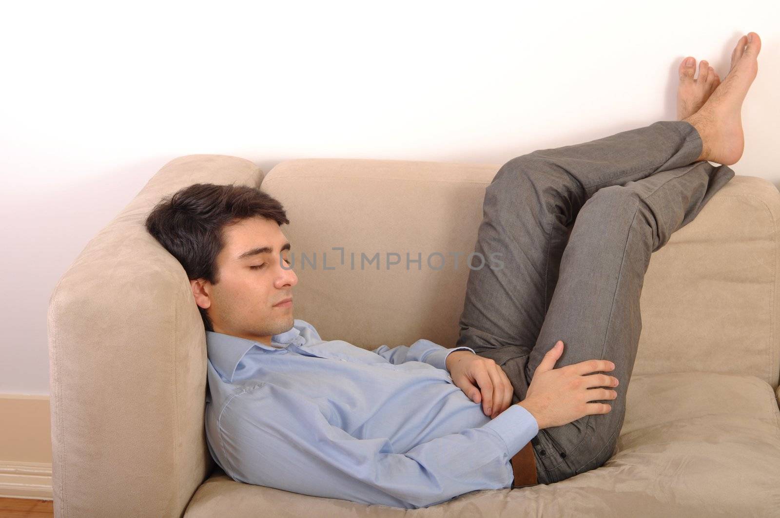 attractive young man sleeping on the couch (isolated on white background)