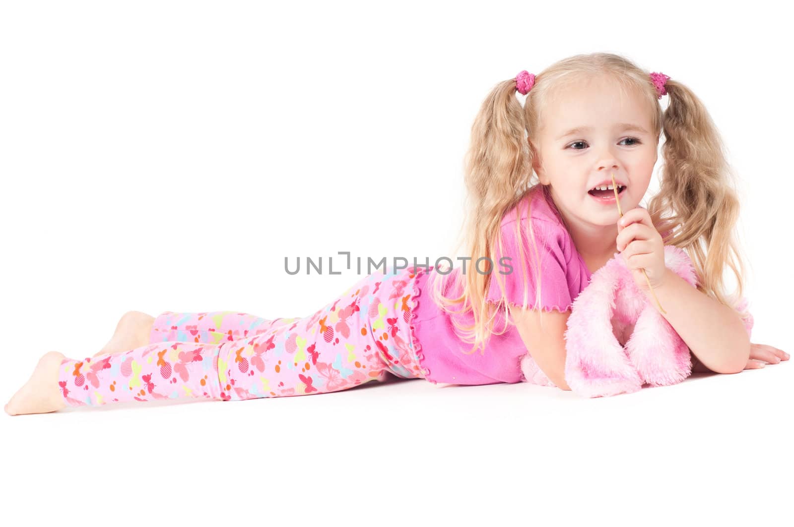 Little cute girl in pink and with ponytails in studio