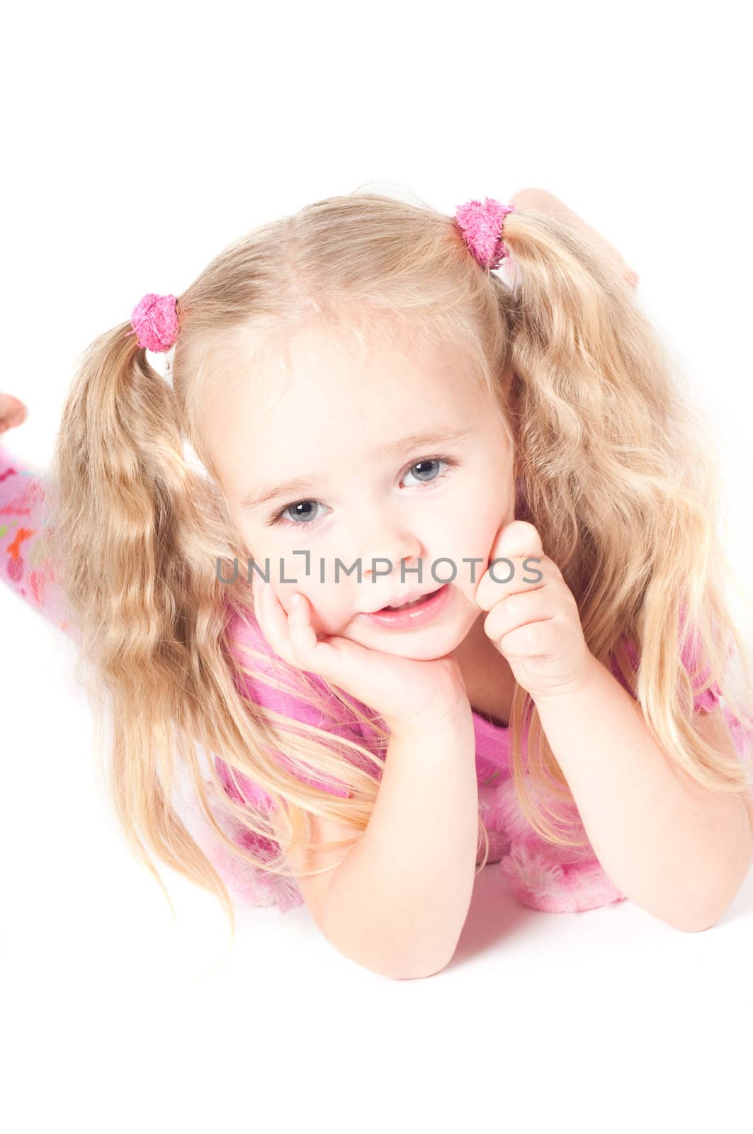 Little cute girl in pink and with ponytails in studio