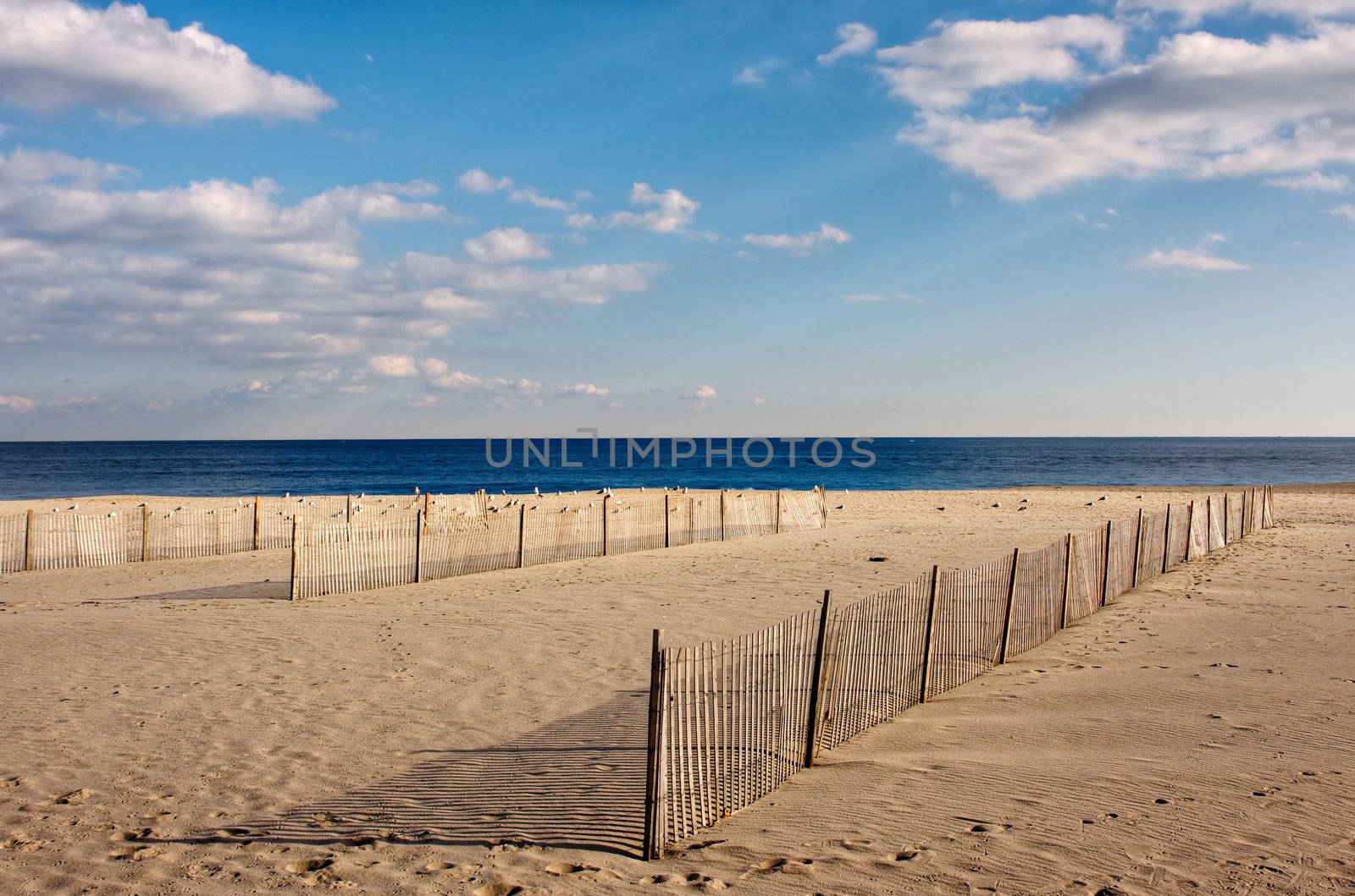 Wooden fences on the beach, The fences are on the sand in the foreground with the ocean and sky above.