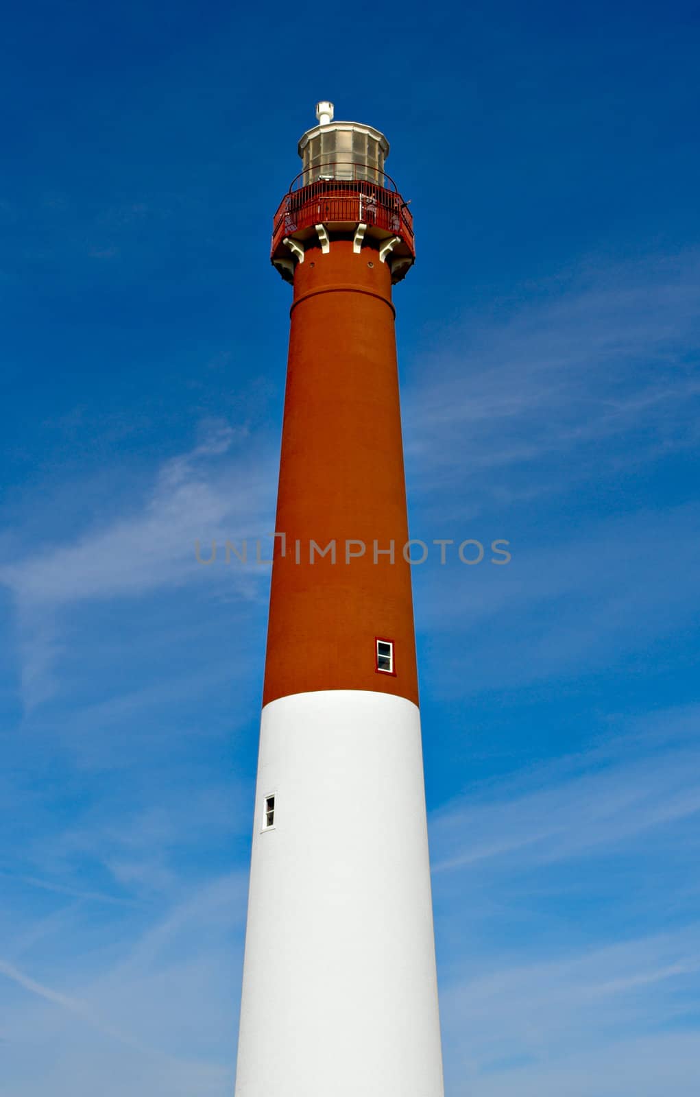 A red and white lighthouse against a blue sky.
