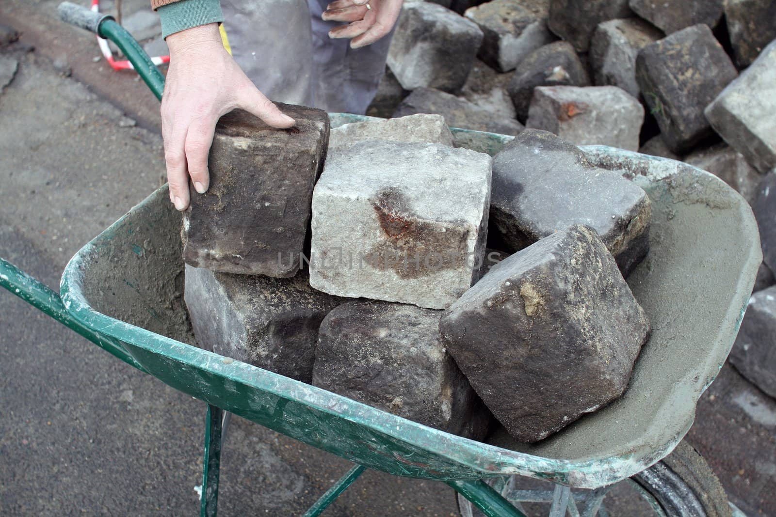 a man transports stones in a wheelbarrow, for repair the pavement