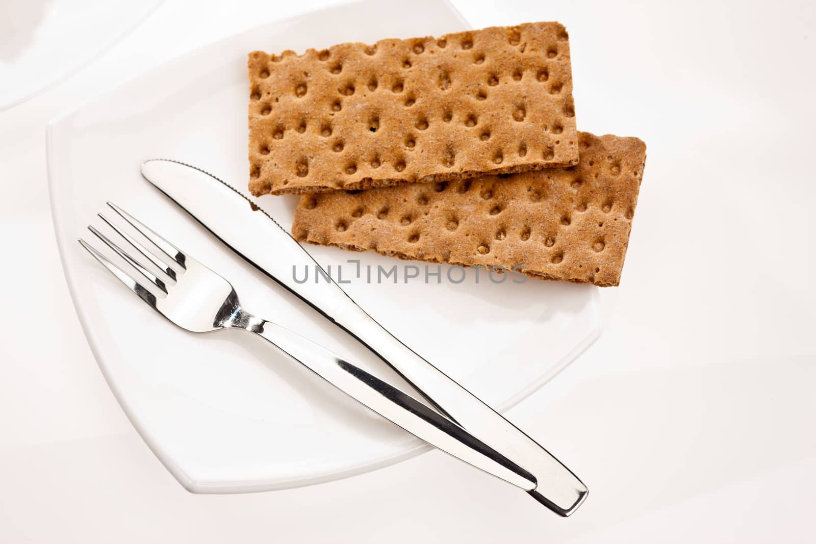 crusty bread with fork and knife on white plate