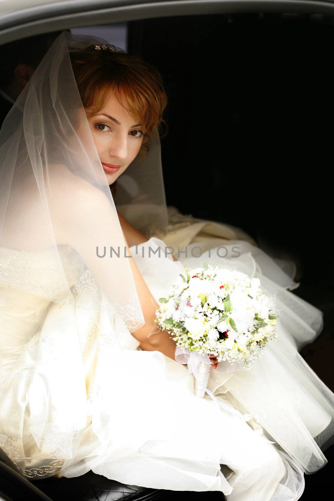 Beautiful the bride with a bouquet in the automobile