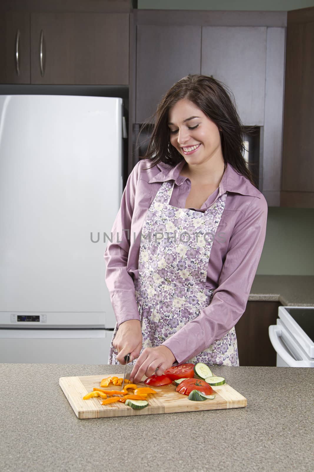 Young woman wearing an apron in a kitchen, cutting vegetables