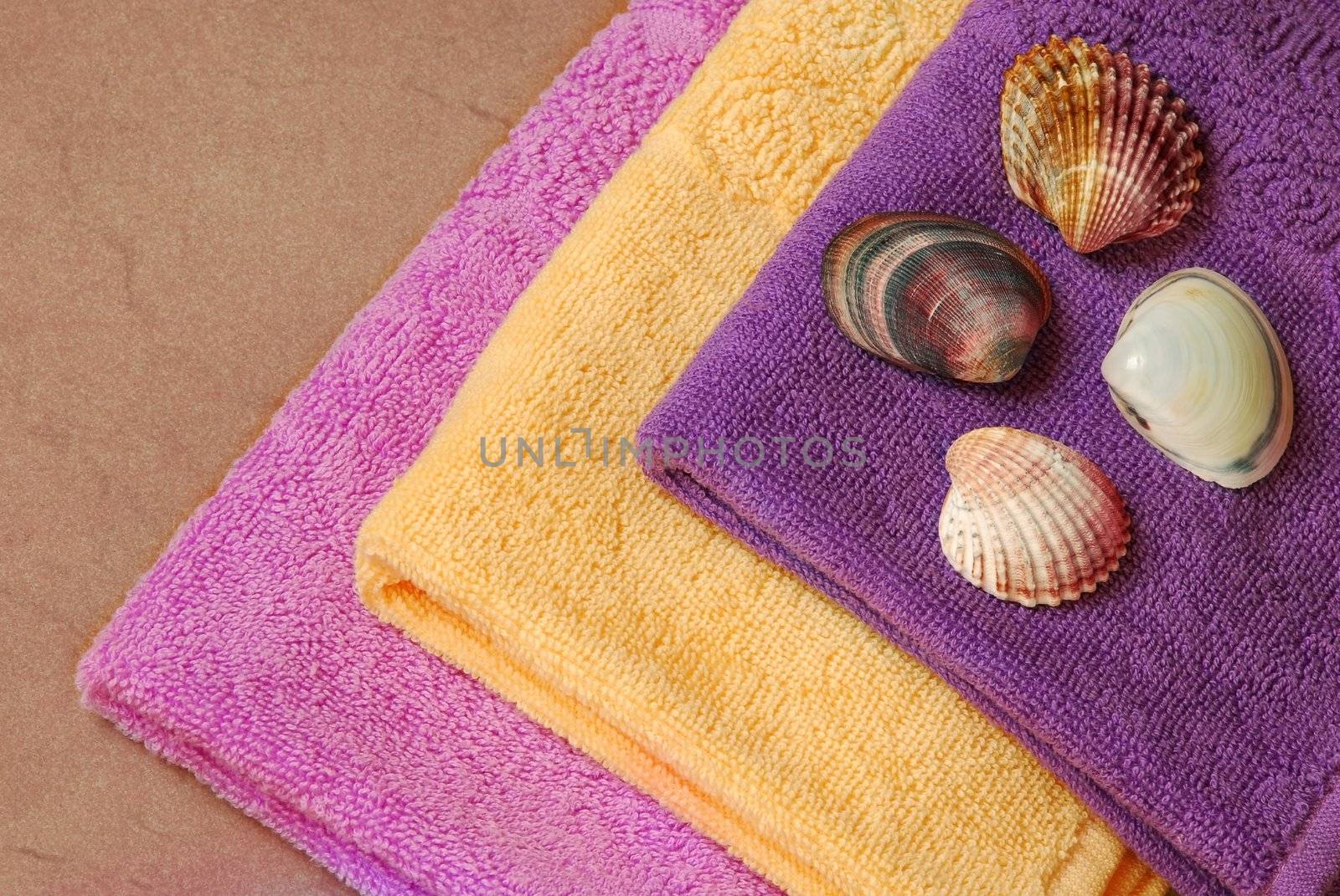 pile of new yellow, magenta and purple cotton towels with a shells