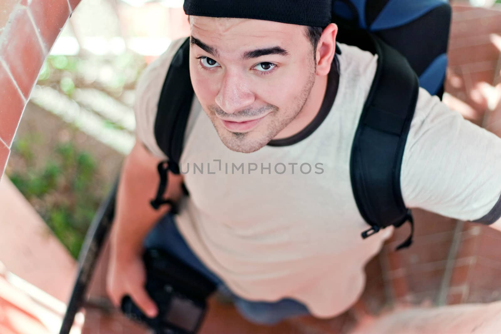 A young photographer in his late twenties with his camera backpack and dslr in hand walking down a spiral staircase. Shallow depth of field.