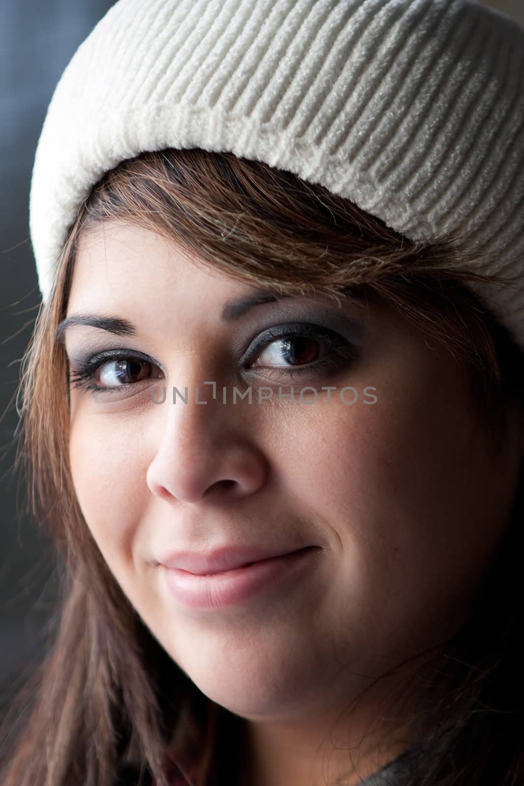 A Hispanic brunette woman with a friendly smile on her face wearing a knit cap on her head.