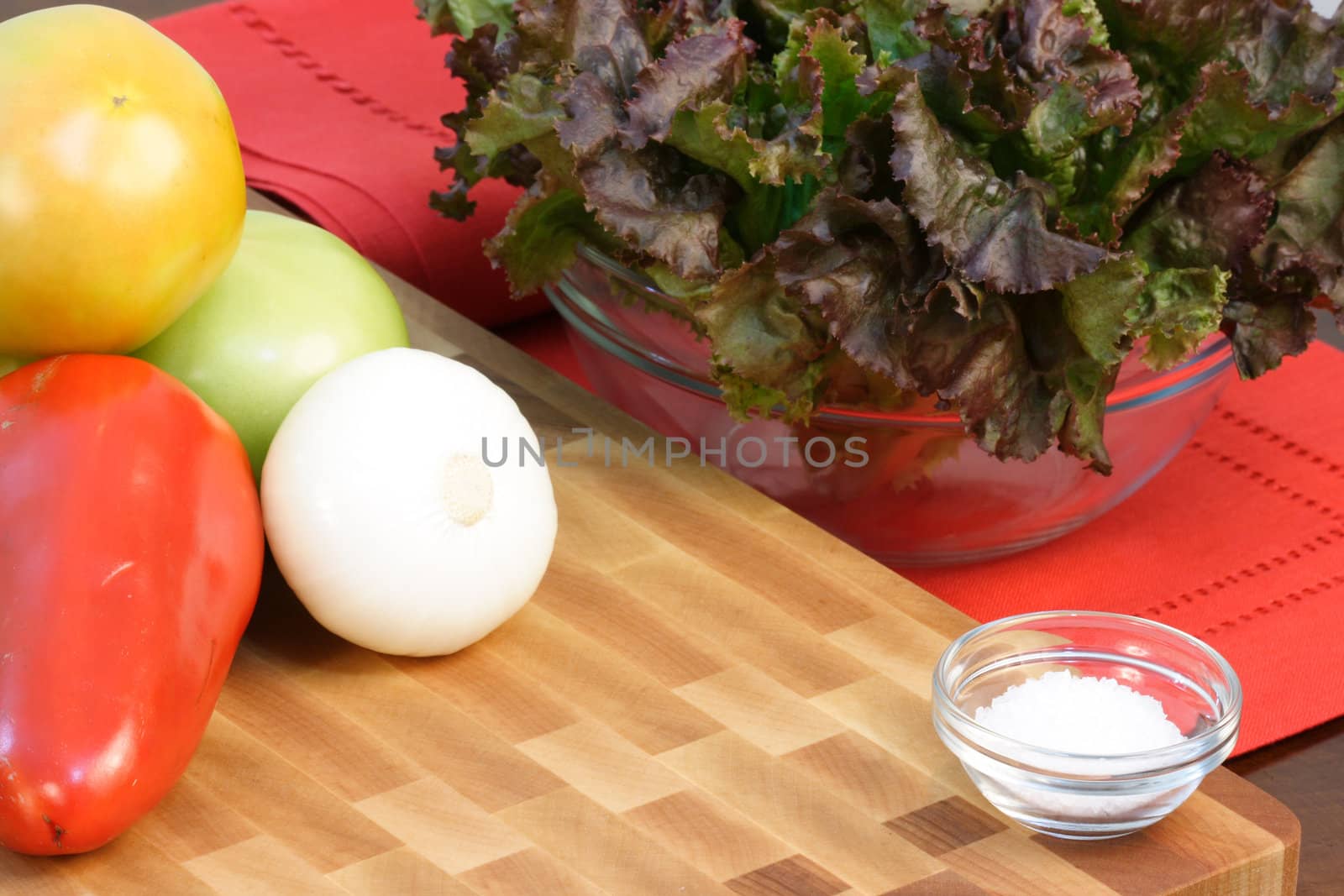 assorted organic vegetables with coarse salt and fancy wood cutting board and linen tablecloth 