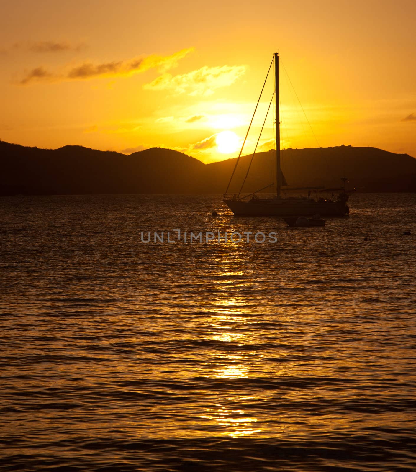 Silhouette of a sailing boat in front of the setting sun over the ocean