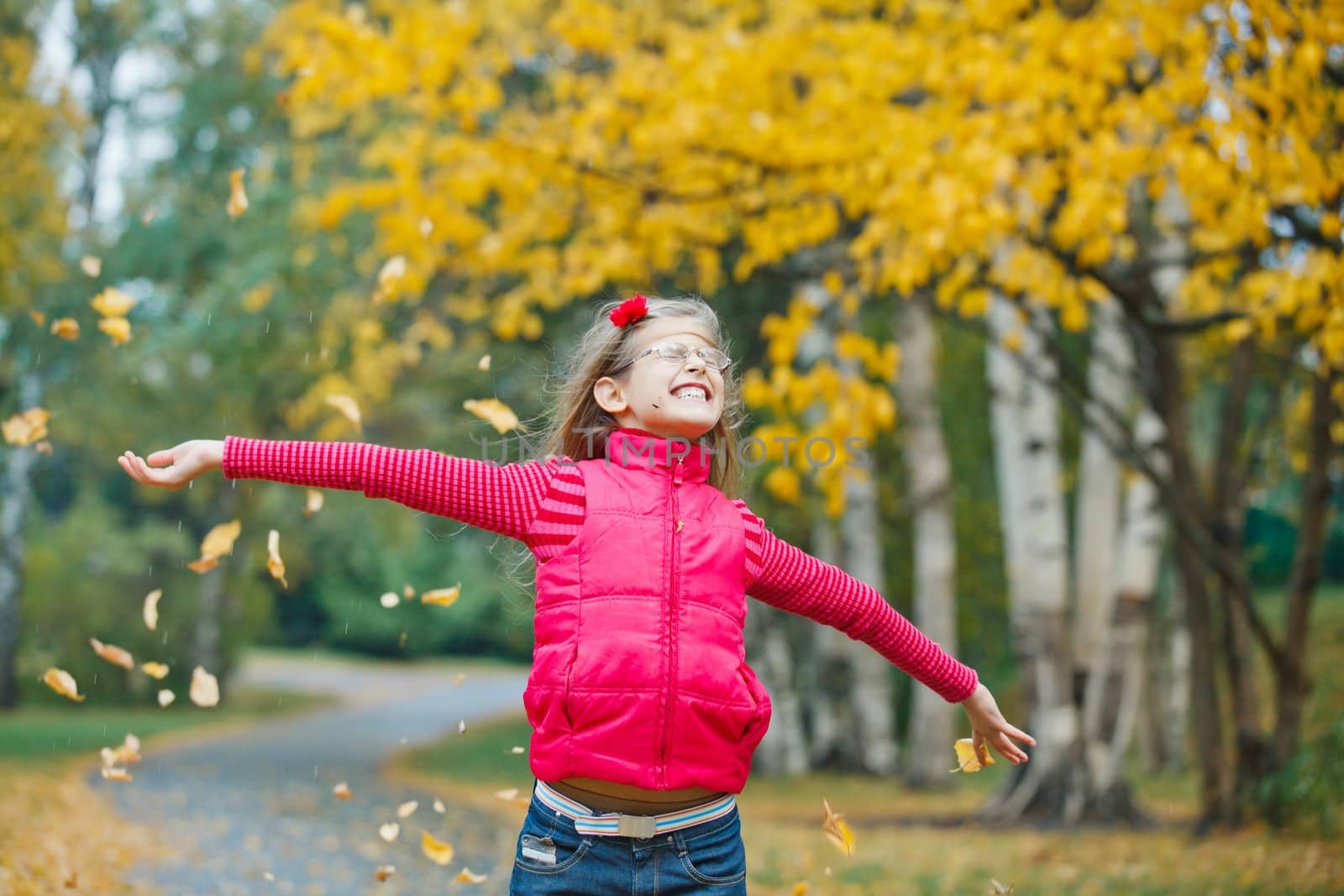 Cute girl walking in the autumn park. Rain, yellow leaves, tree.