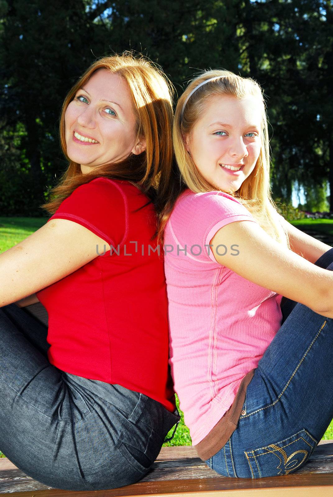 Portrait of a mother with teenage daughter relaxing in summer park