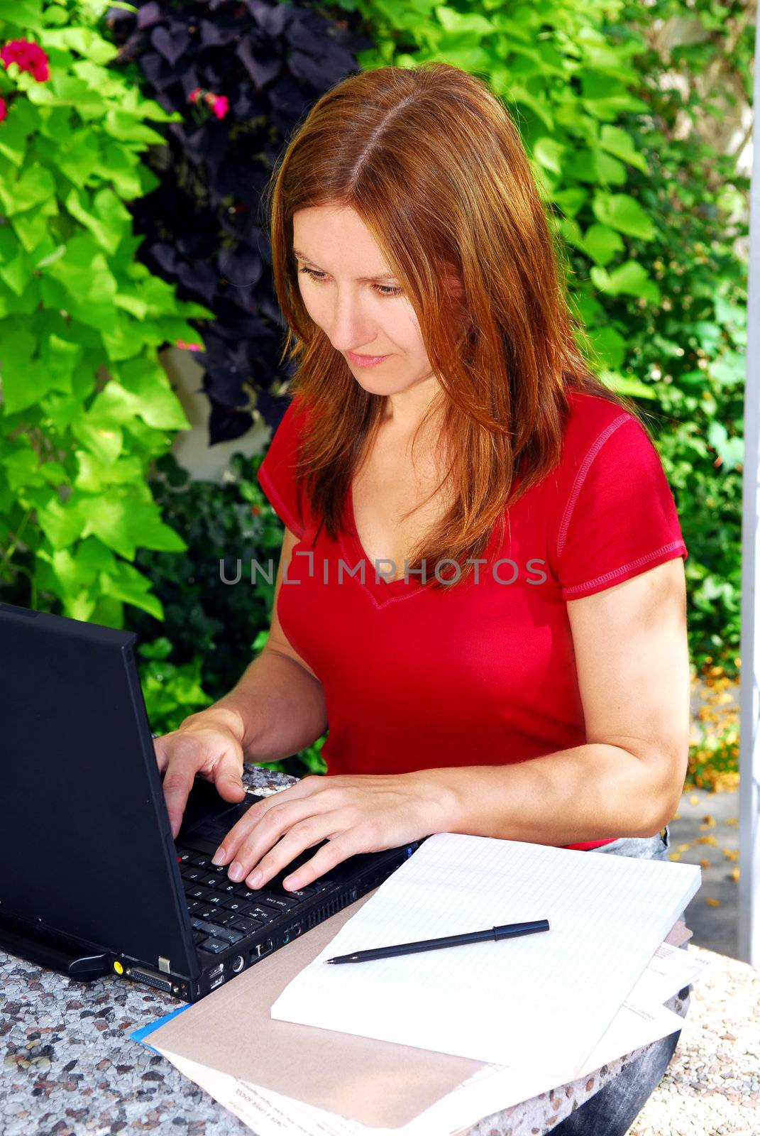 Mature woman working on portable computer in her garden at home