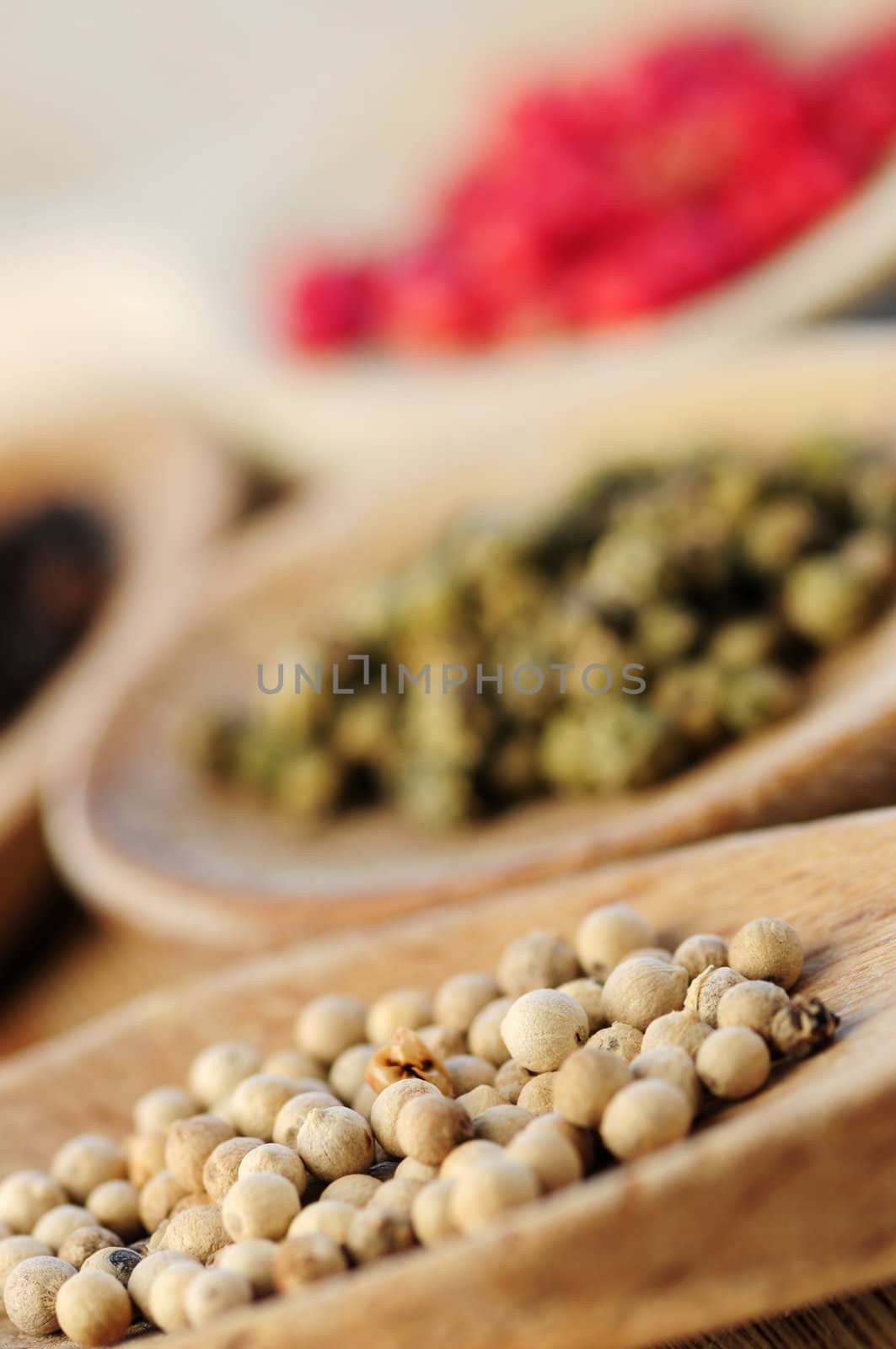 Assorted peppercorns in wooden cooking spoons macro