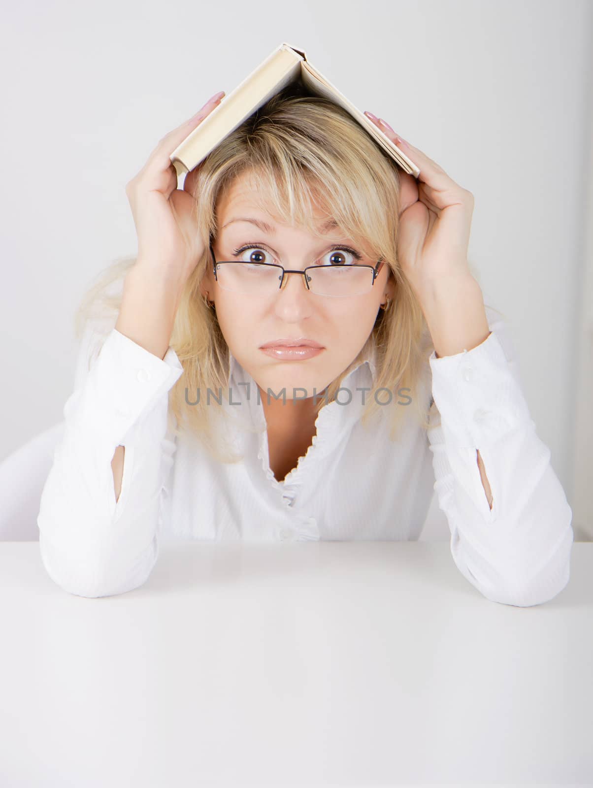 blond girl in glasses hidden under a book
