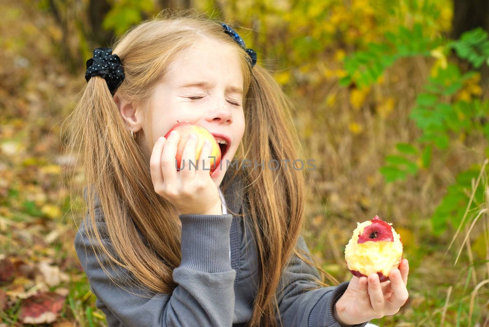 Little girl eating apple outdoors