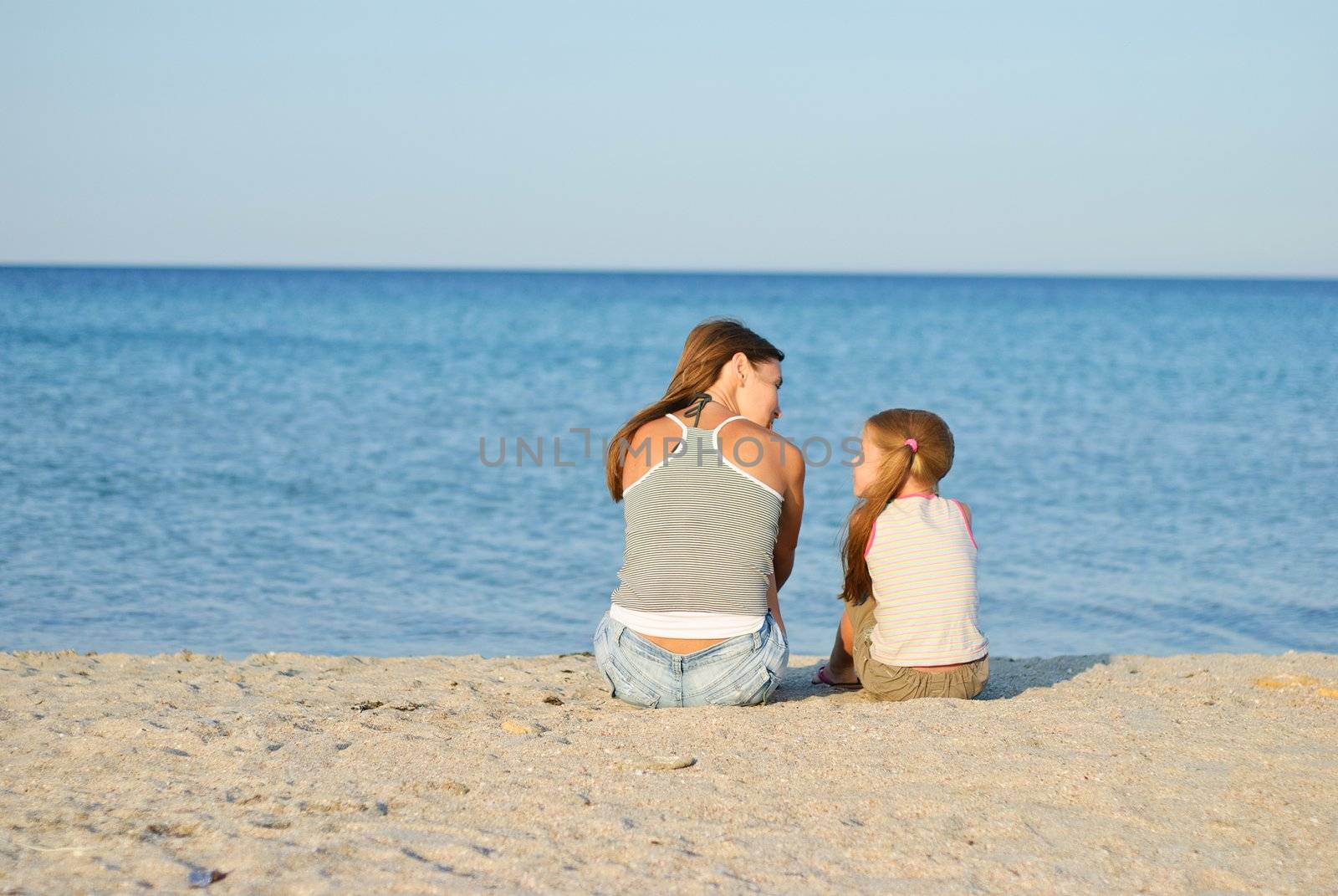 Mother and daughter sitting on the beach