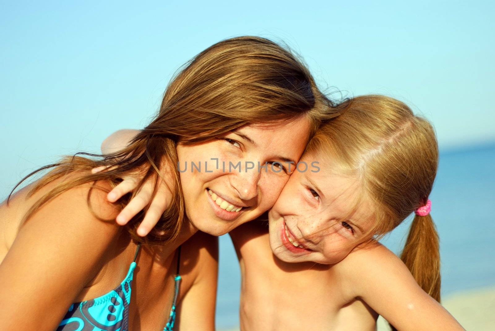 Happy smiling young mother with her daughter on the beach