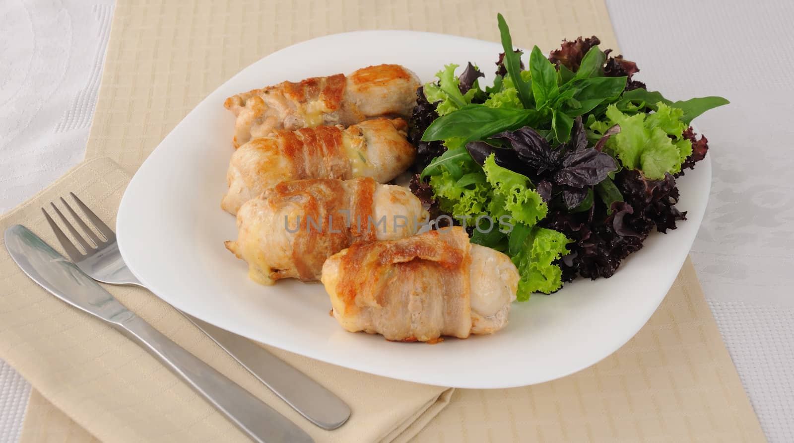 Chicken rolls stuffed with cheese, wrapped in bacon and herbs in a tomato-garlic sauce
