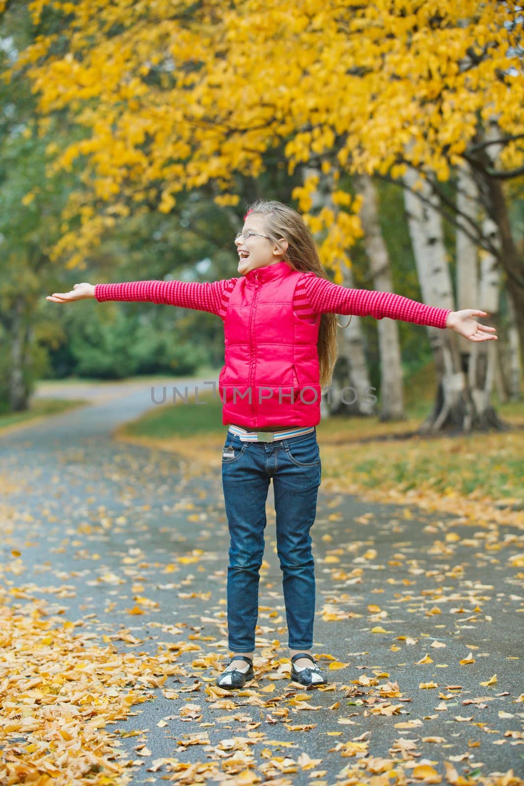 Cute girl walking in the autumn park. Rain, yellow leaves, tree.