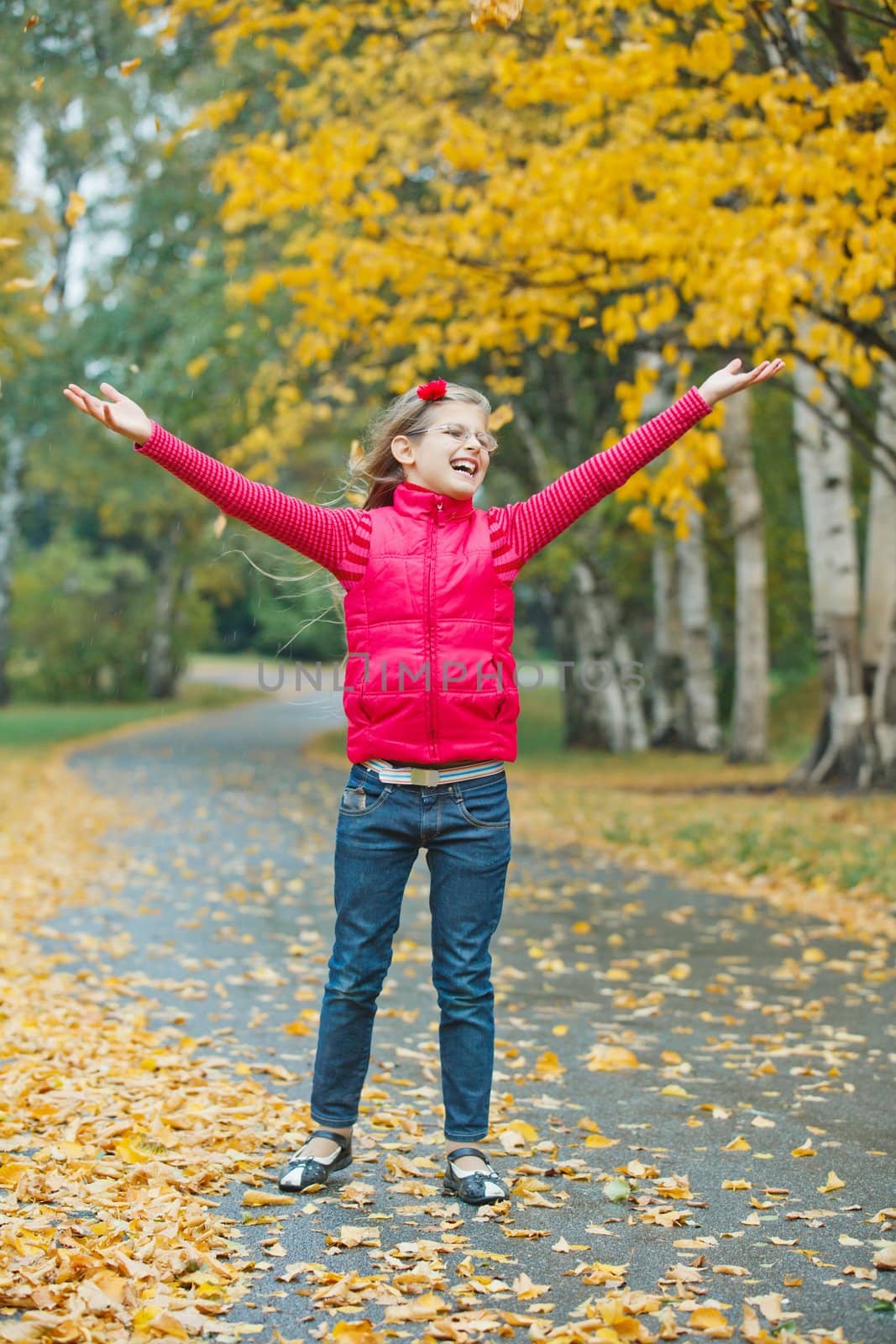 Cute girl walking in the autumn park. Rain, yellow leaves, tree.