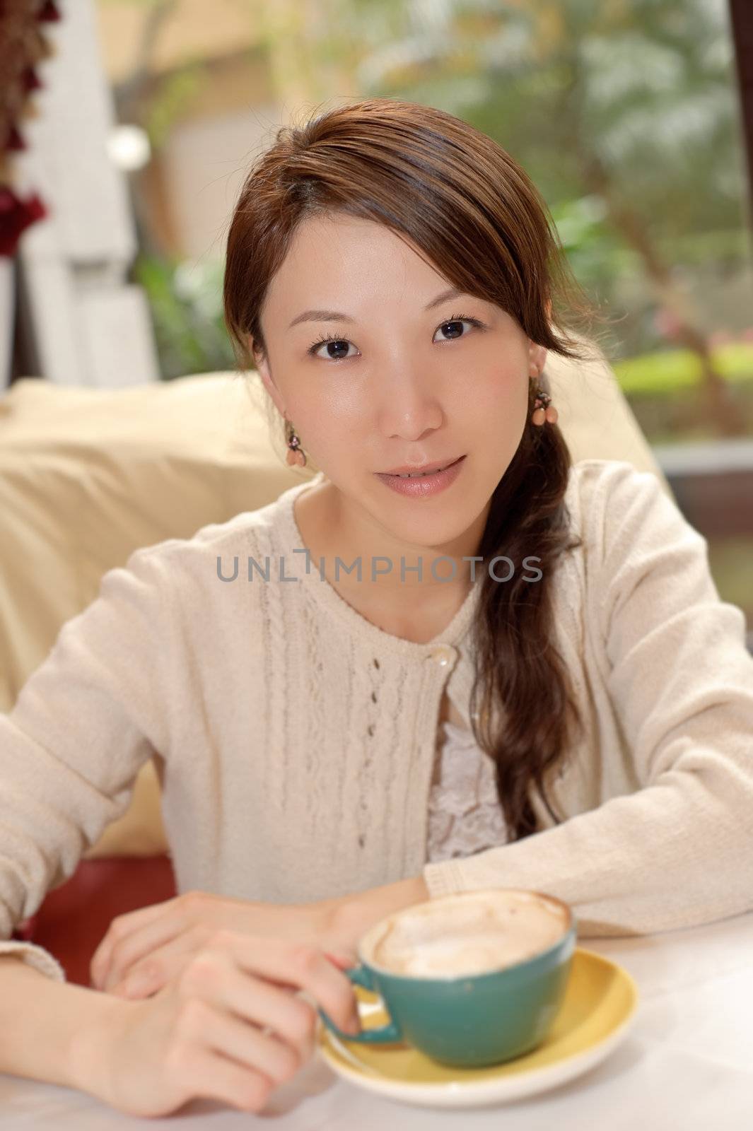 Young Asian lady with cup of coffee in restaurant.