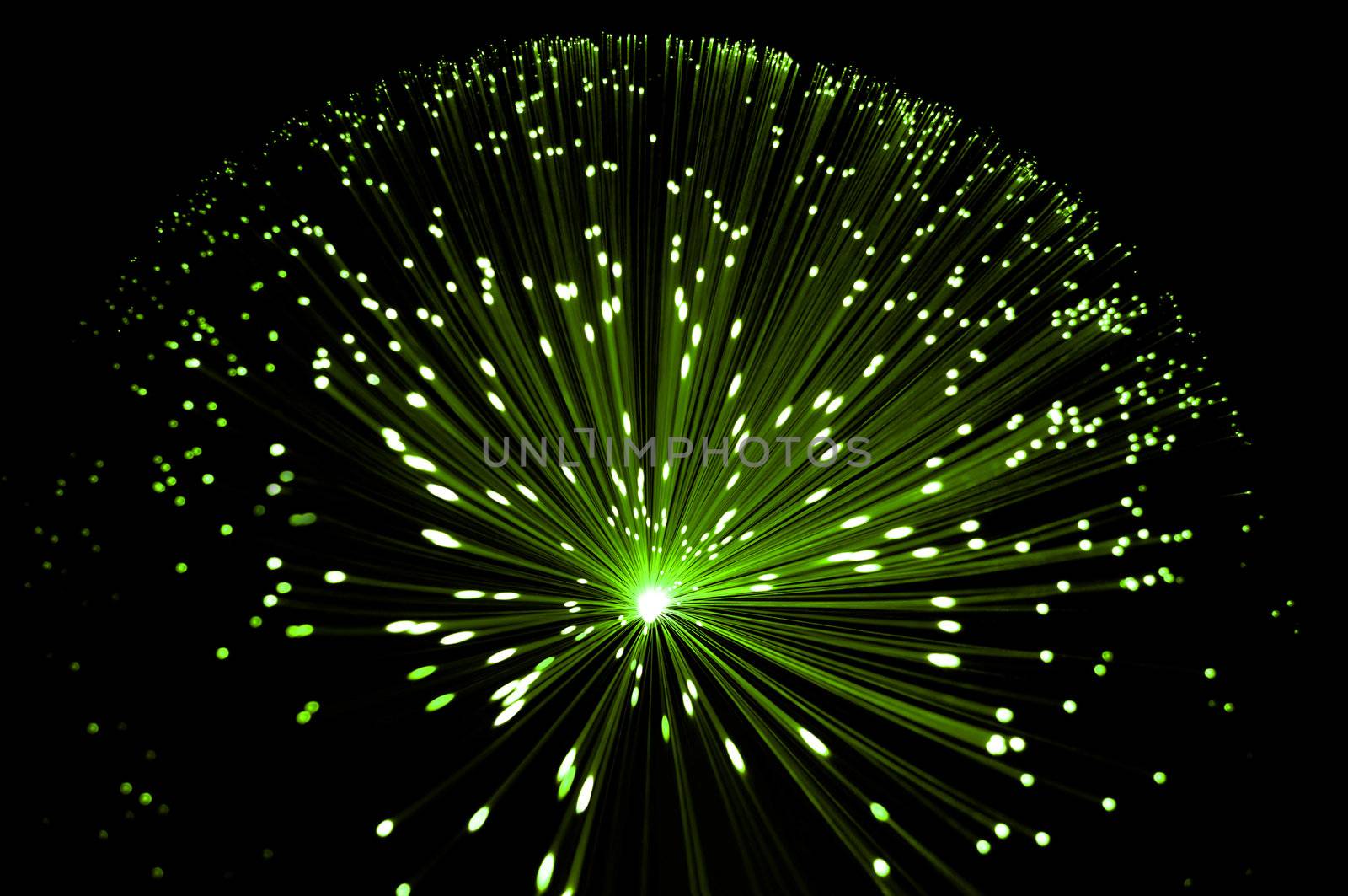 Abstract style overhead view of illuminated fiber optic strands against black.
