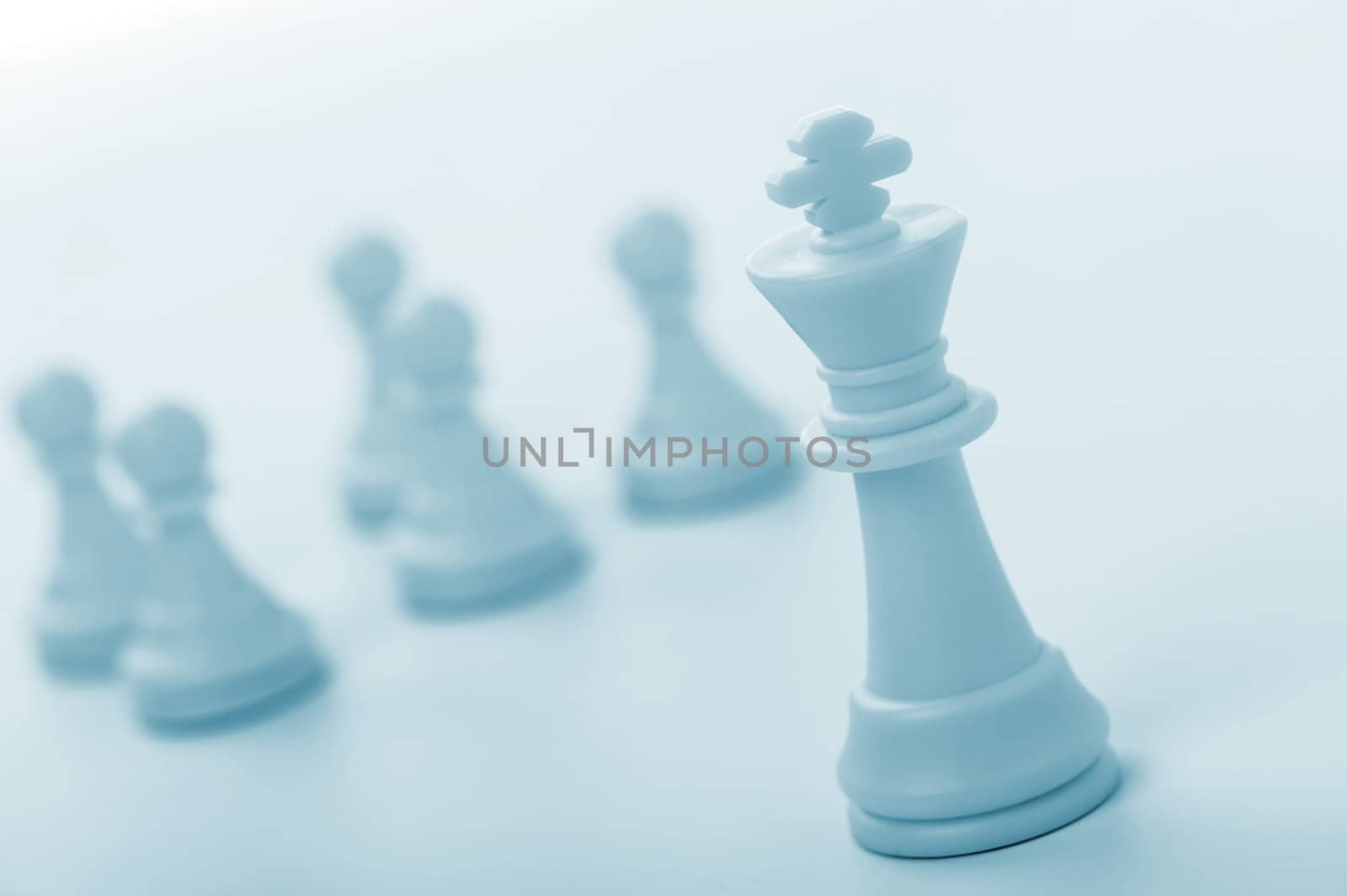 Chess figure - king. Concept of the leader. Pawns on blur a background