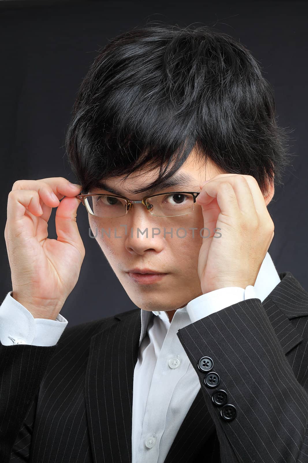 Closeup portrait of a asian young man wearing spectacles against black 