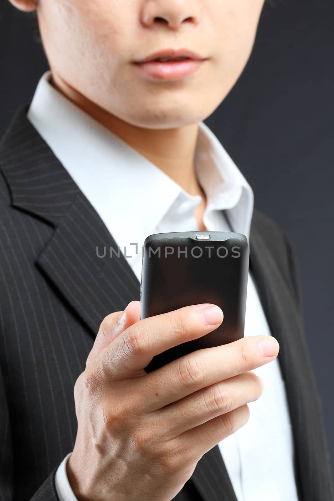 business man in black suit working on pda or smartphone  by cozyta