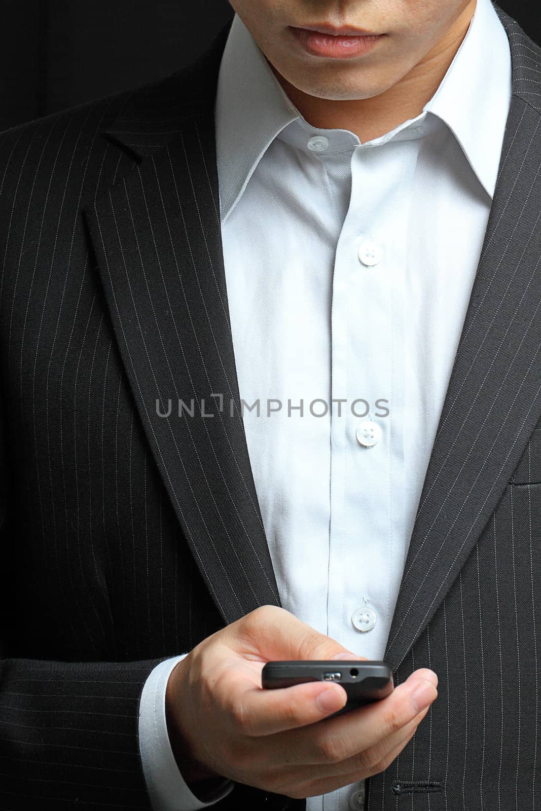 business man in black suit working on pda or smartphone 