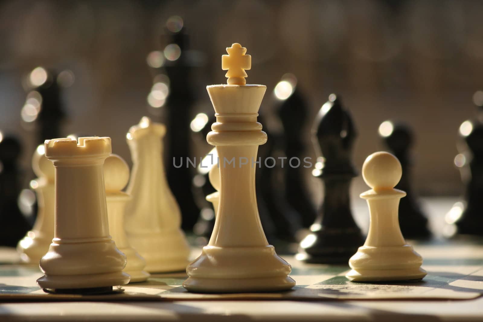 A white king stands on a chessboard waiting for the next attack.