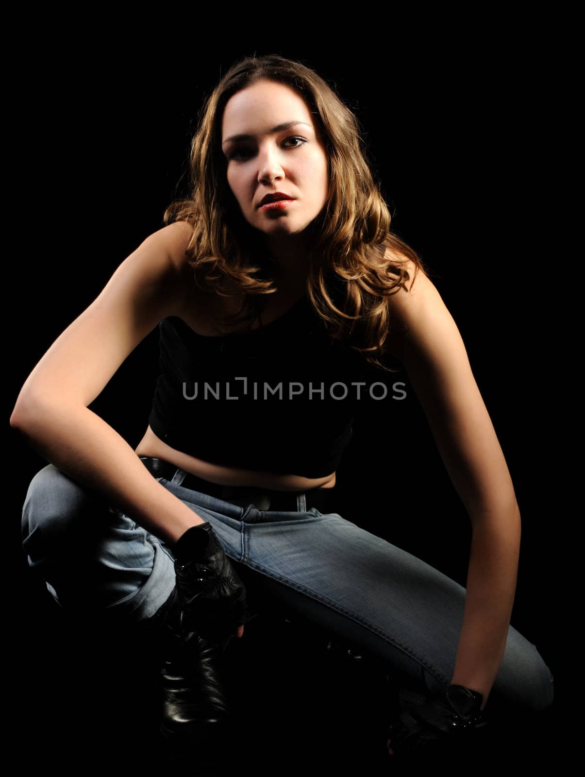 The beautiful woman on a black background. Jeans and black blouse