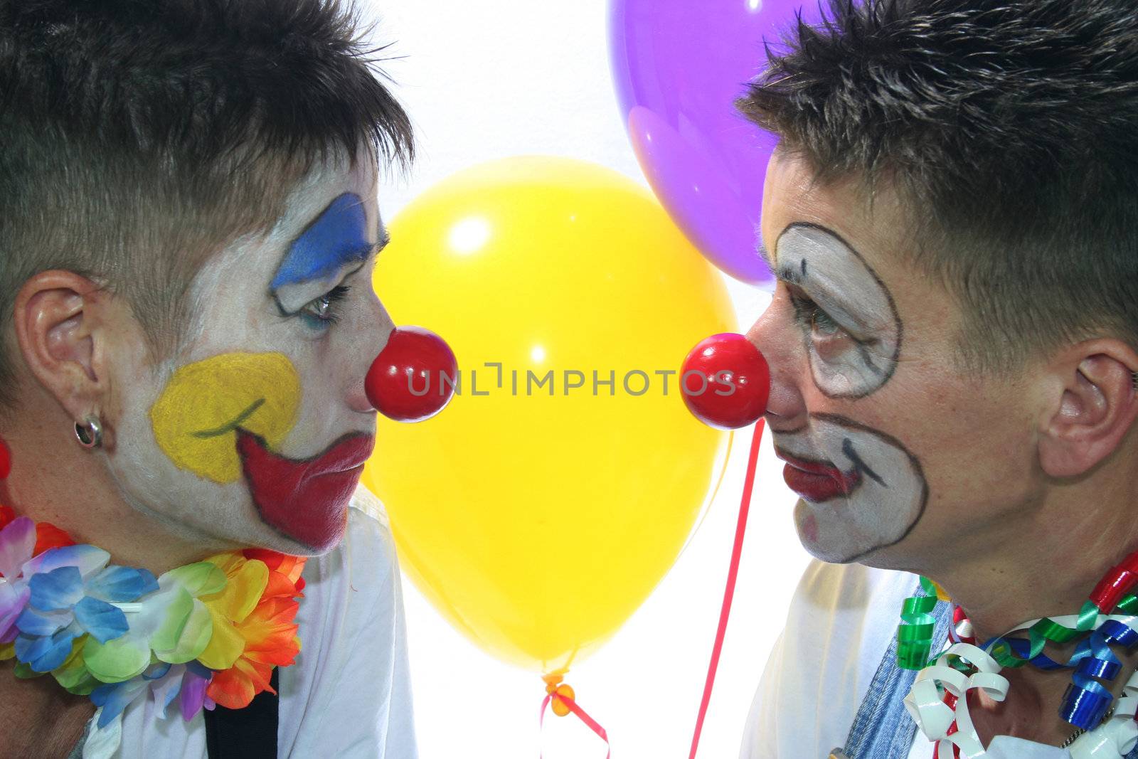 Two clowns look at each other with red nose