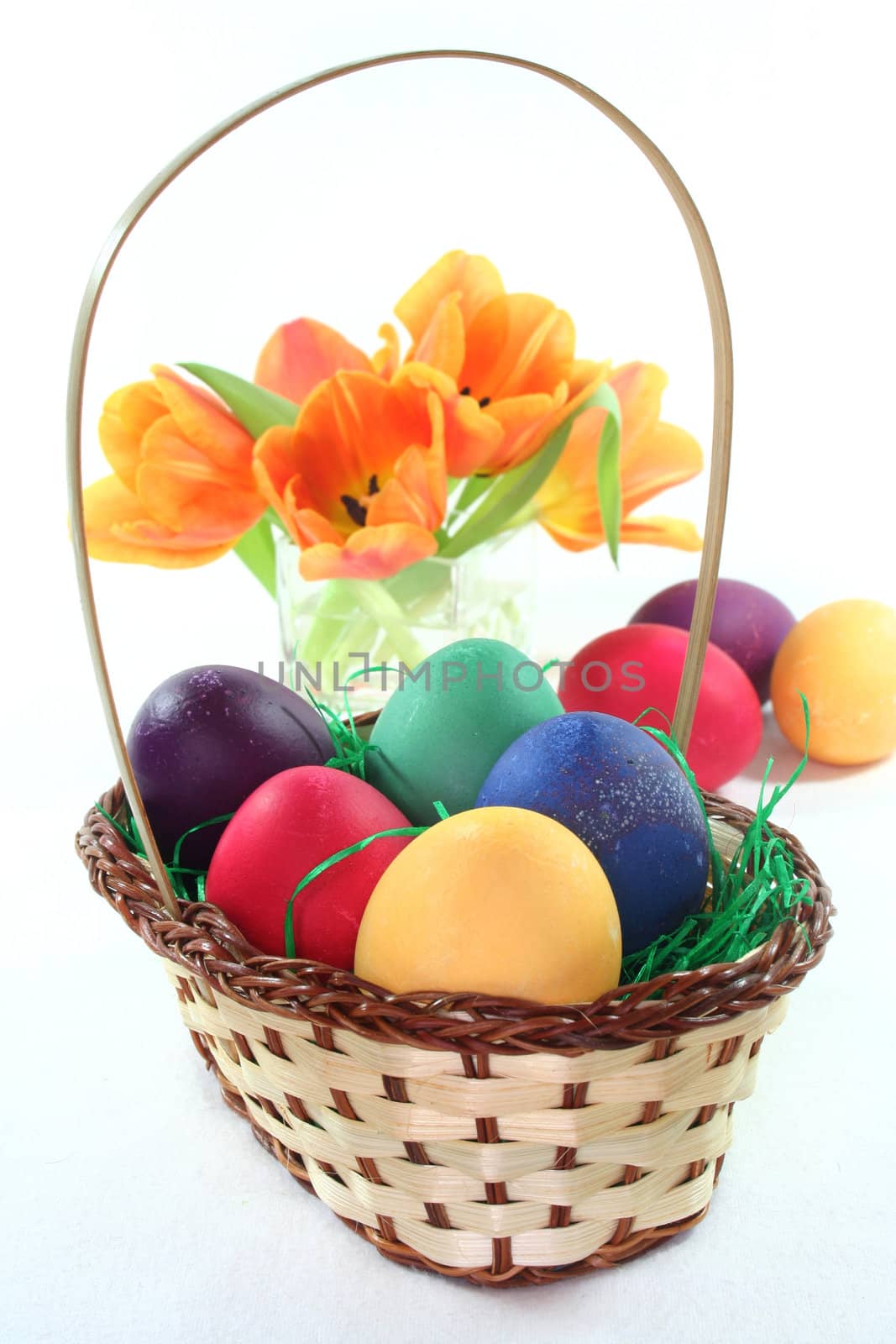 Easter basket with Easter eggs and tulips on a white background