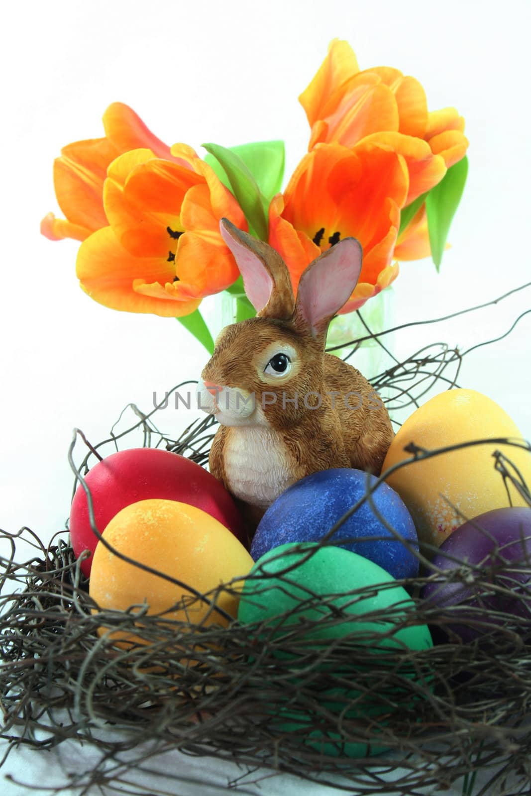 Easter basket with Easter eggs and Easter bunny and tulips on a white background