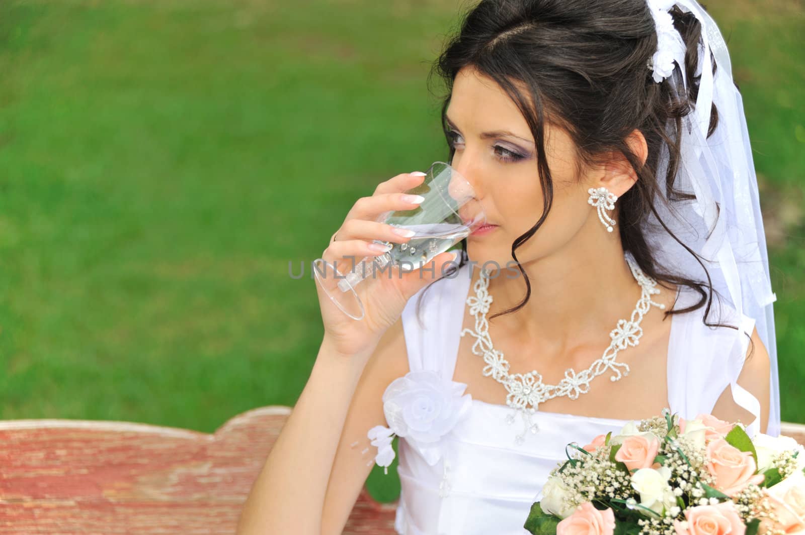 The bride drinking a champagne. The young girl in a wedding dress.