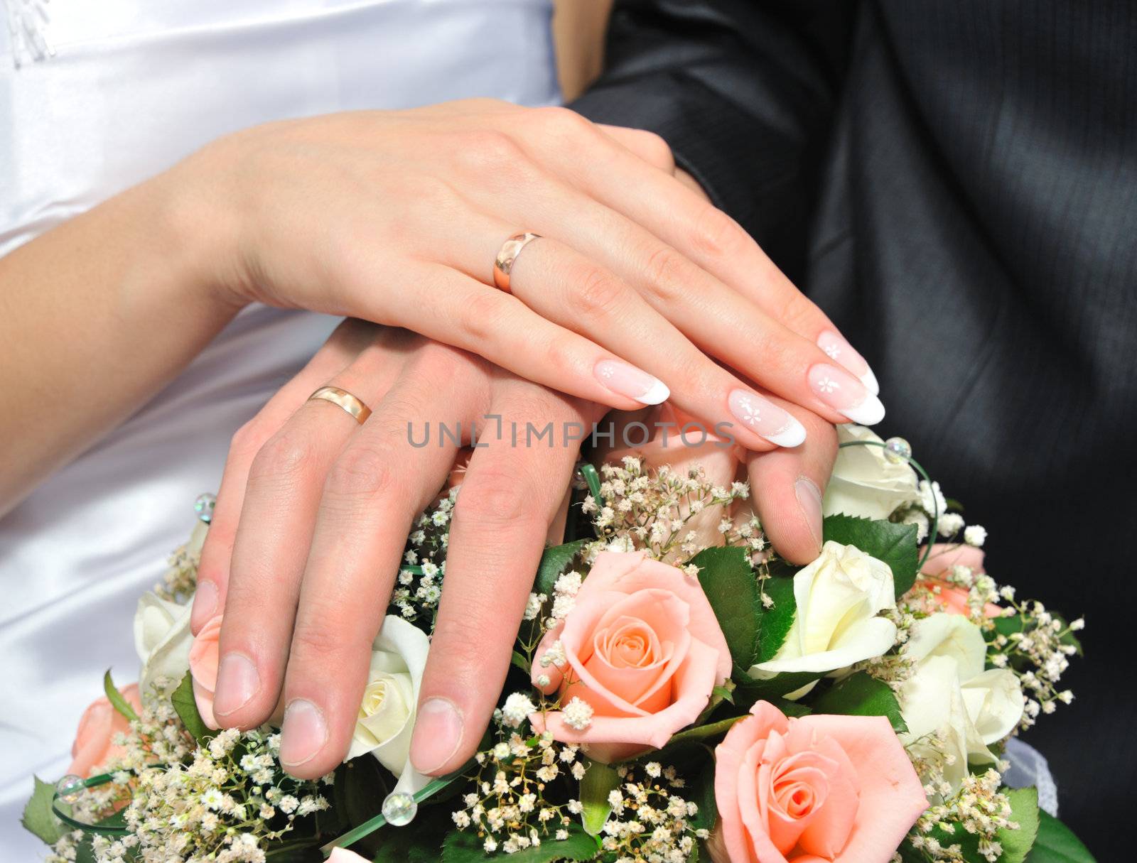 Hands of a newly-married couple. Tenderness of the groom and the bride above wedding a bouquet