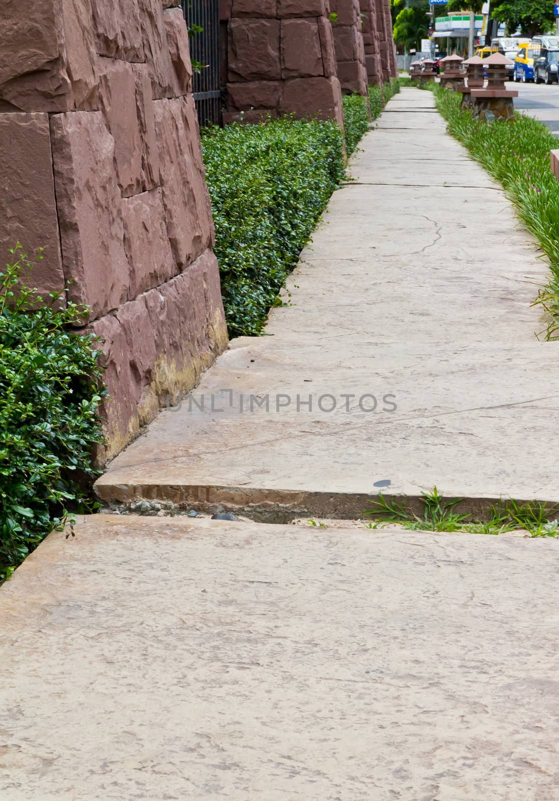 Walkway beside the fence, steel and stone walls of the hotel.