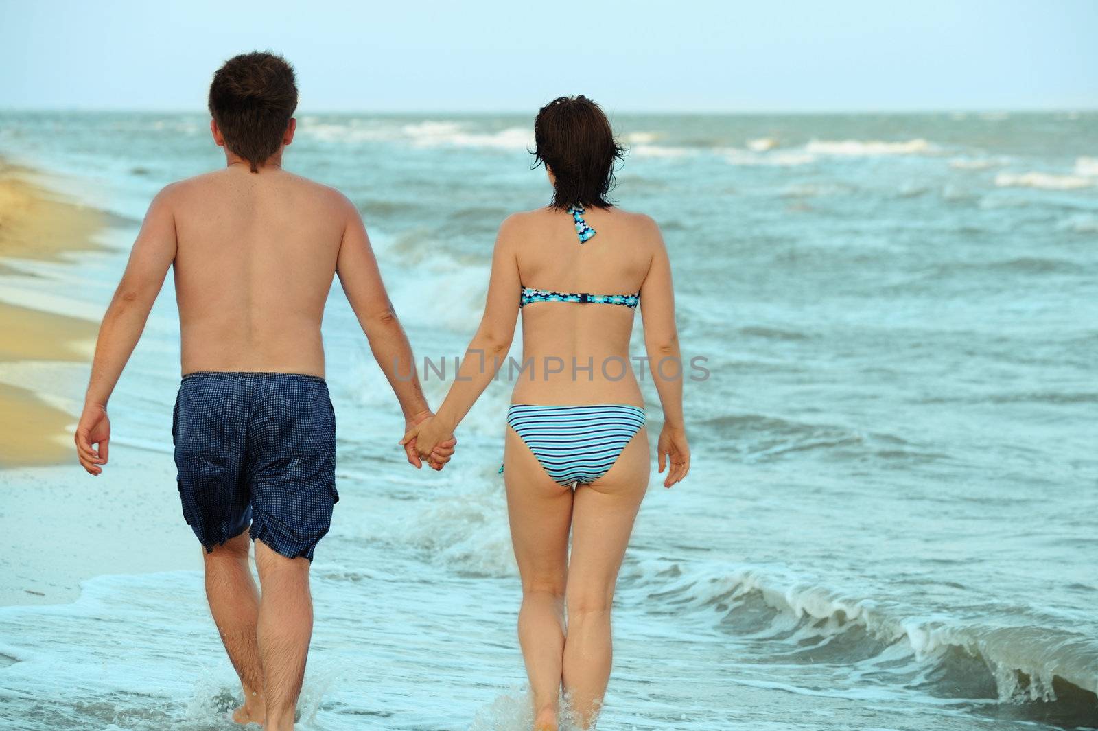 Pair on seacoast. The enamoured guy and the girl walking on coast