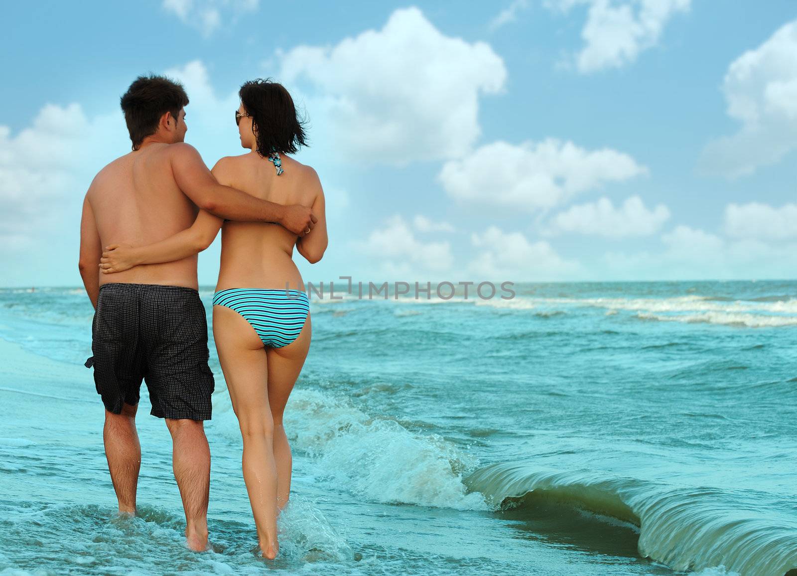 Pair on seacoast. The enamoured guy and the girl walking on coast