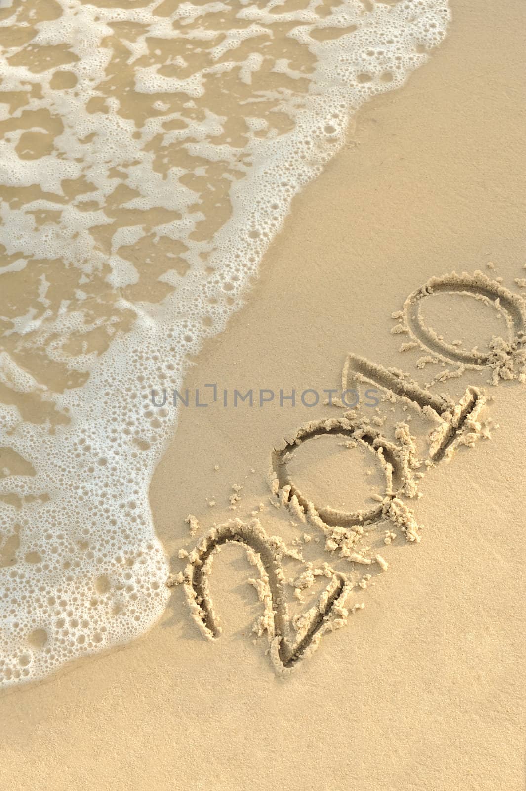 Inscription "2010" on sand. Sea coast with a rolling wave on an inscription