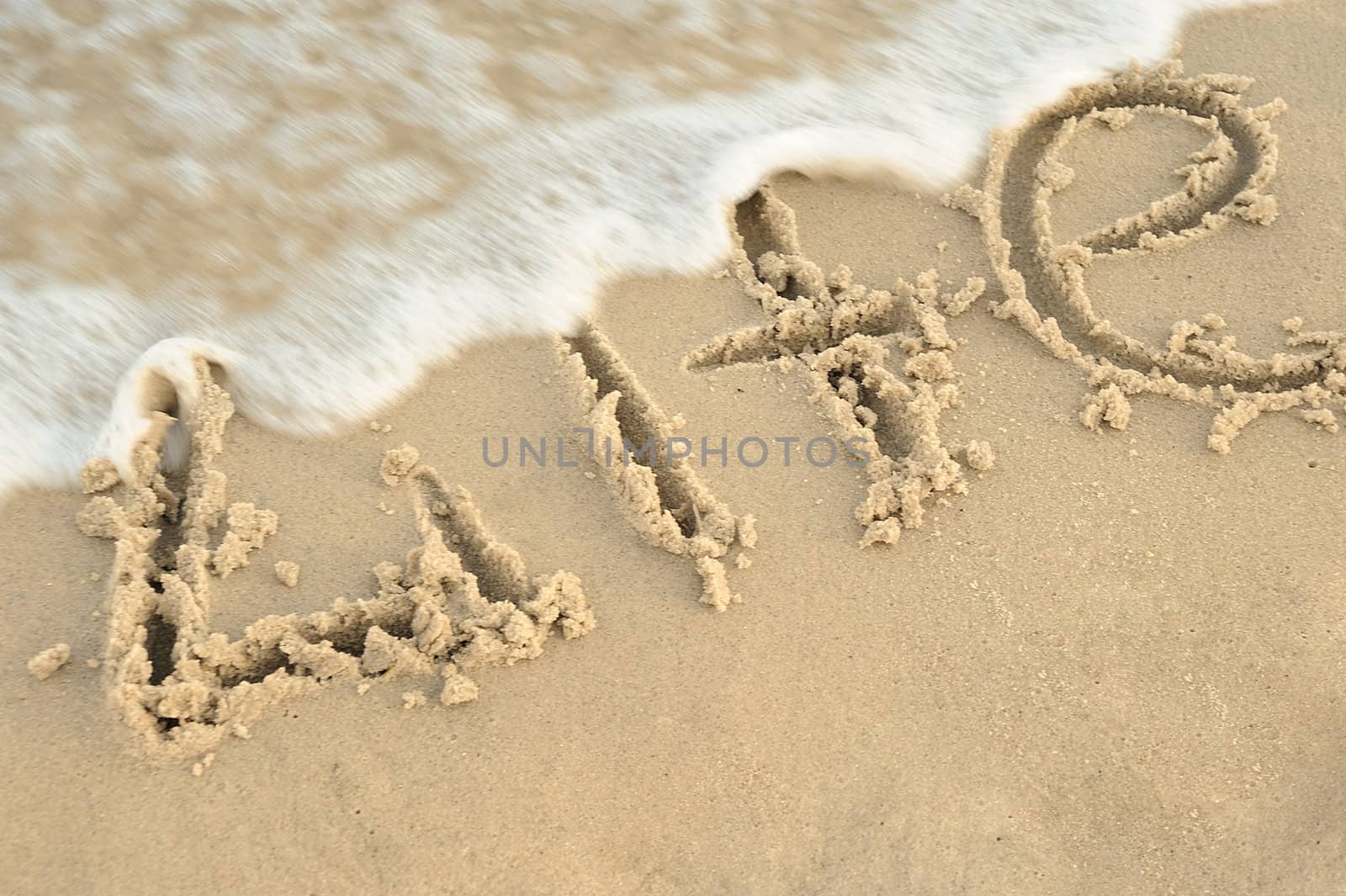 Inscription "life" on sand. Sea coast with a rolling wave on an inscription