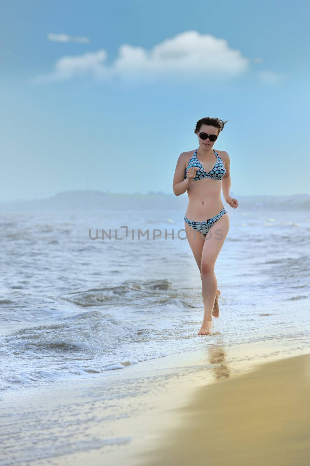 The girl running on seacoast. The European appearance in sunglasses